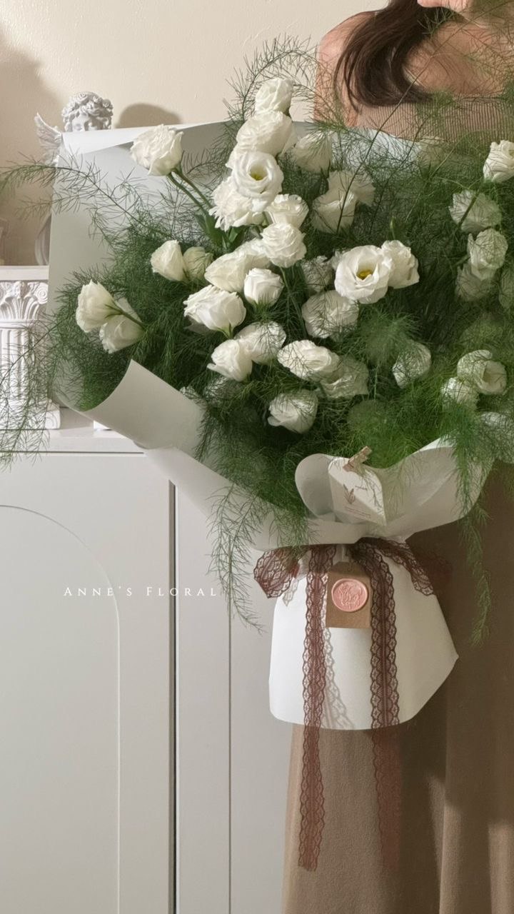 一束丰盛的白色与绿色花束，以浅色包装衬托。