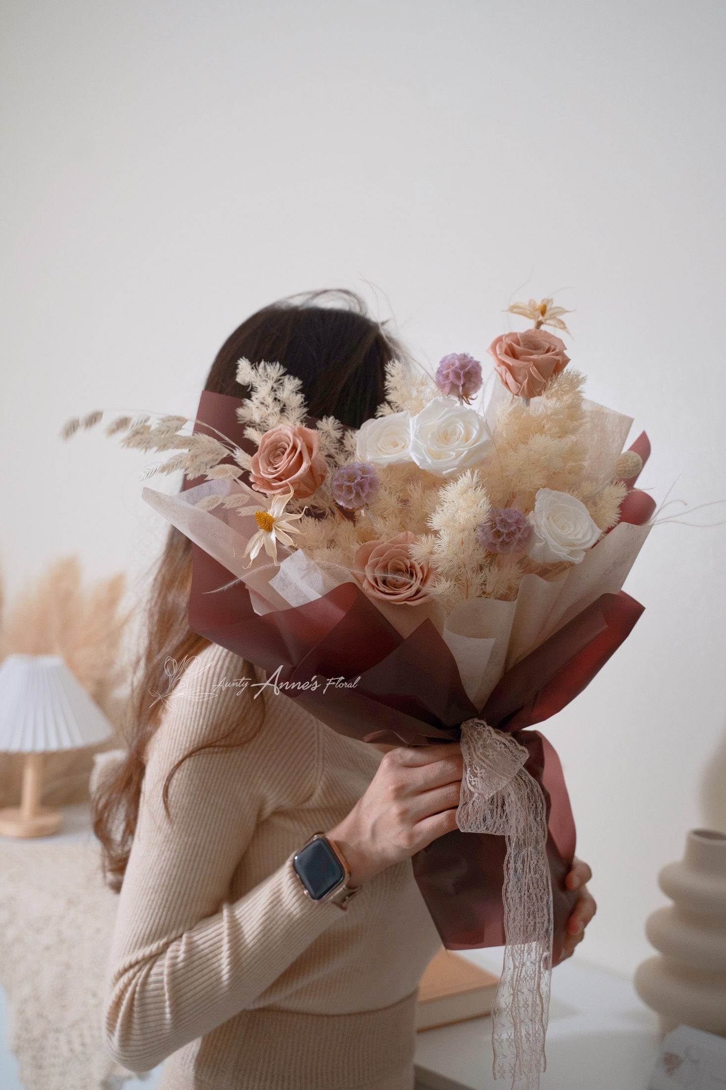 一位女子手捧柔色花束，身影映在镜前。